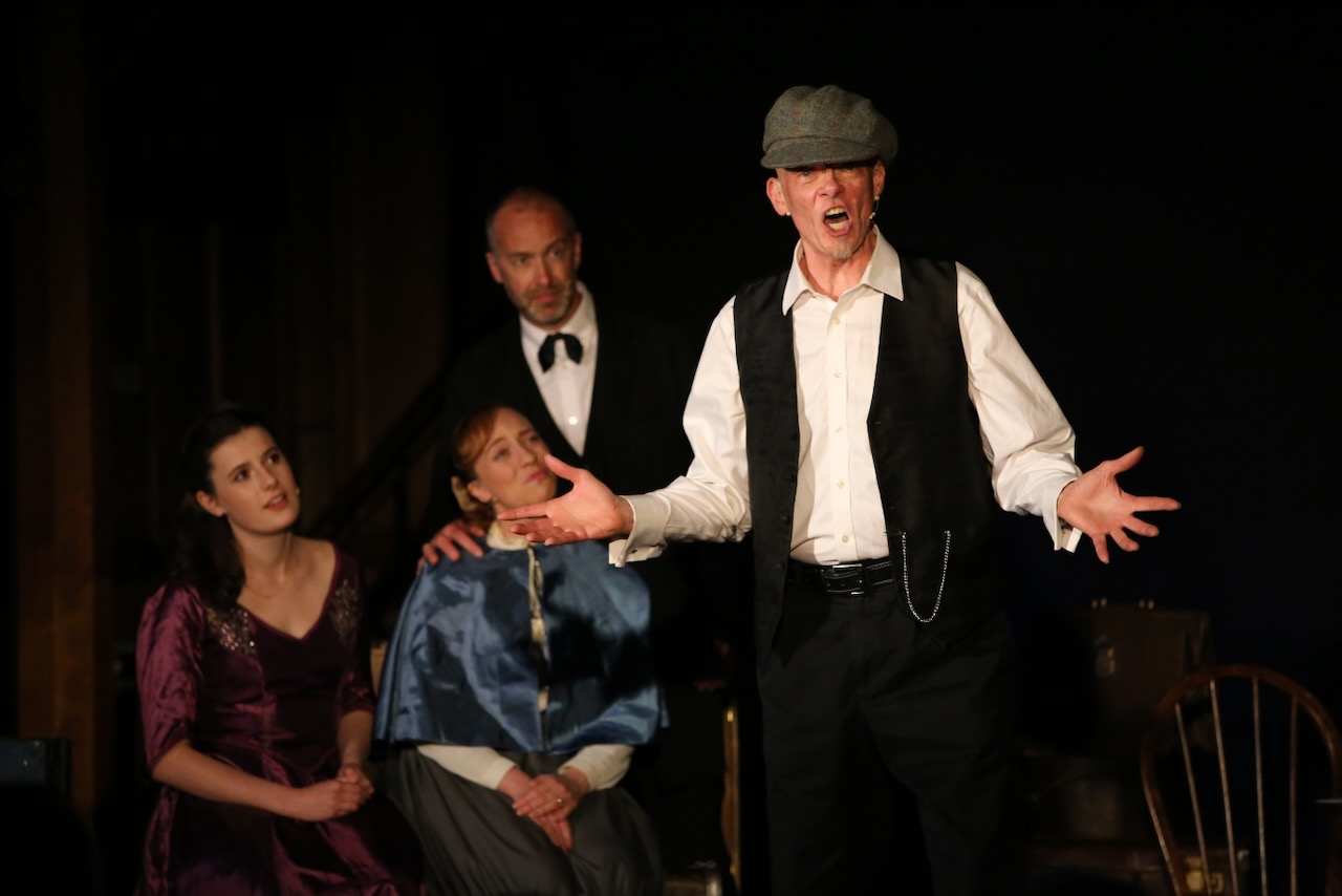 An actor sings a solo while others look on in the background
