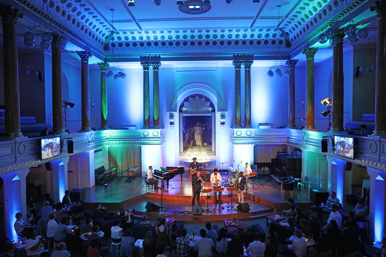 Wide view of The Roots of Jazz on stage in a large hall lit in blue
