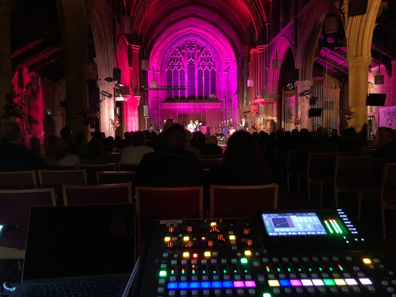 Sound desk view of a traditional church venue washed in pink light