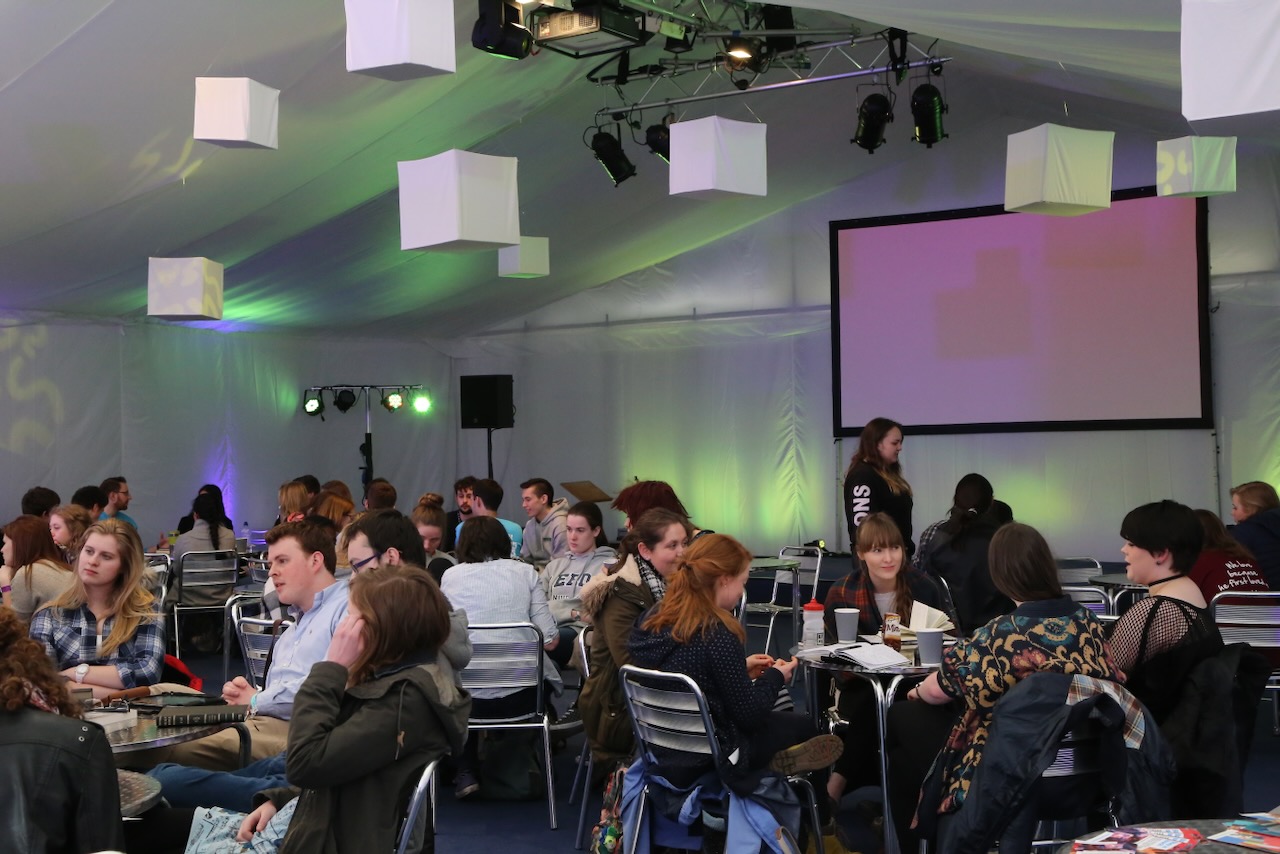 Marquee in the daytime with students sat around tables